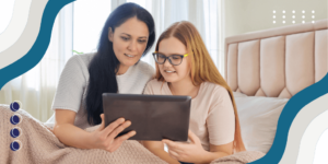 A mother and daughter using a tablet in bed to look at education and careers options.